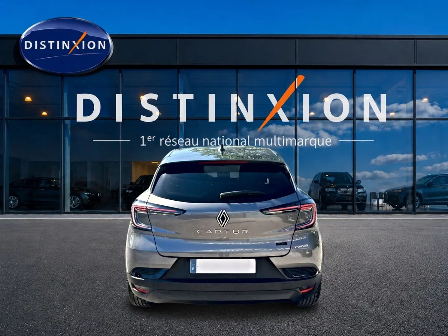 Vue arrière d'un Renault Captur gris cassiopée 2026, avec feux LED et logo distinctif sur fond de vitrine Distinxion.