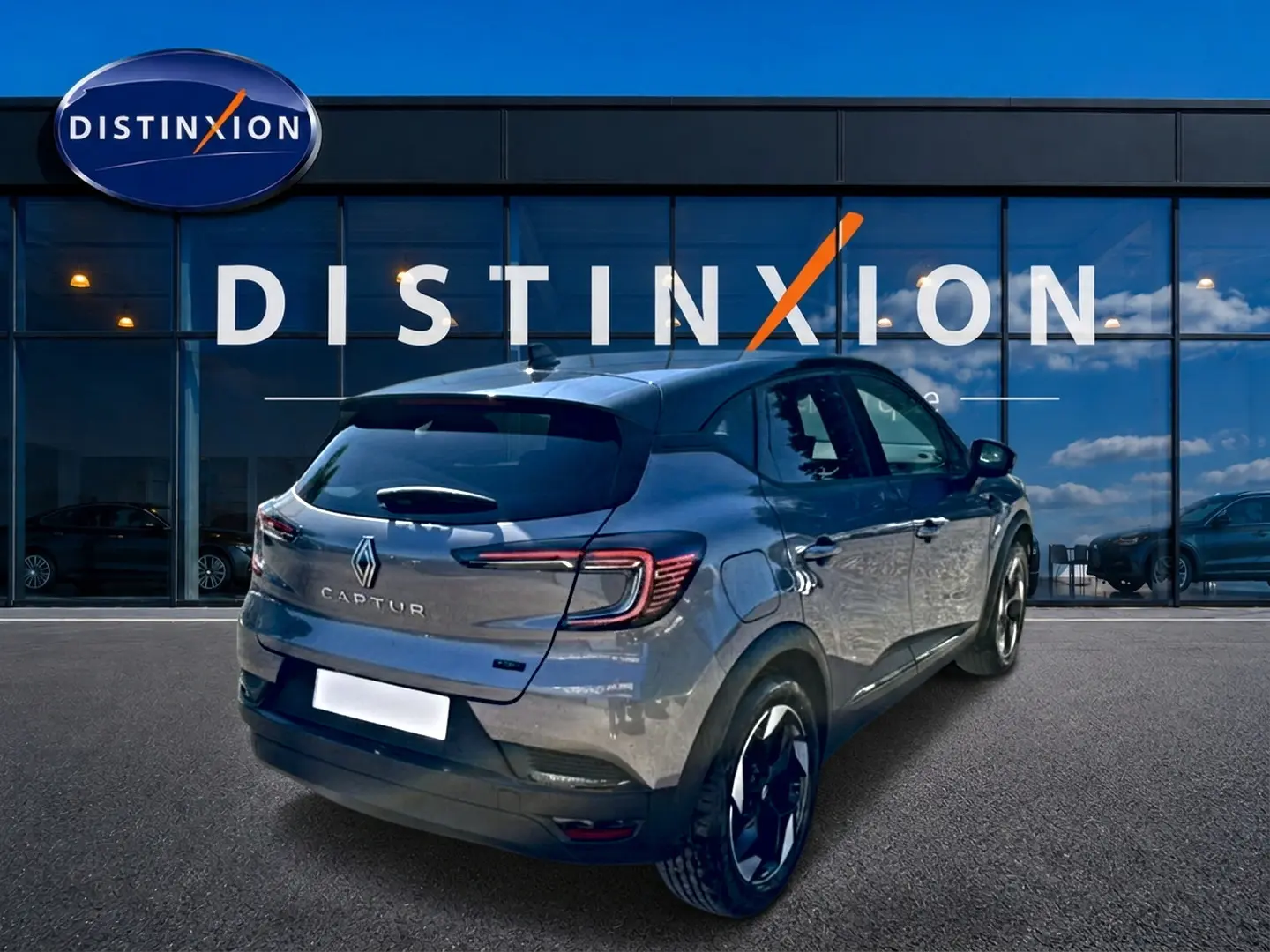 Vue 3/4 arrière droite d'un Renault Captur gris cassiopée 2026 devant une vitrine avec logo Distinxion.