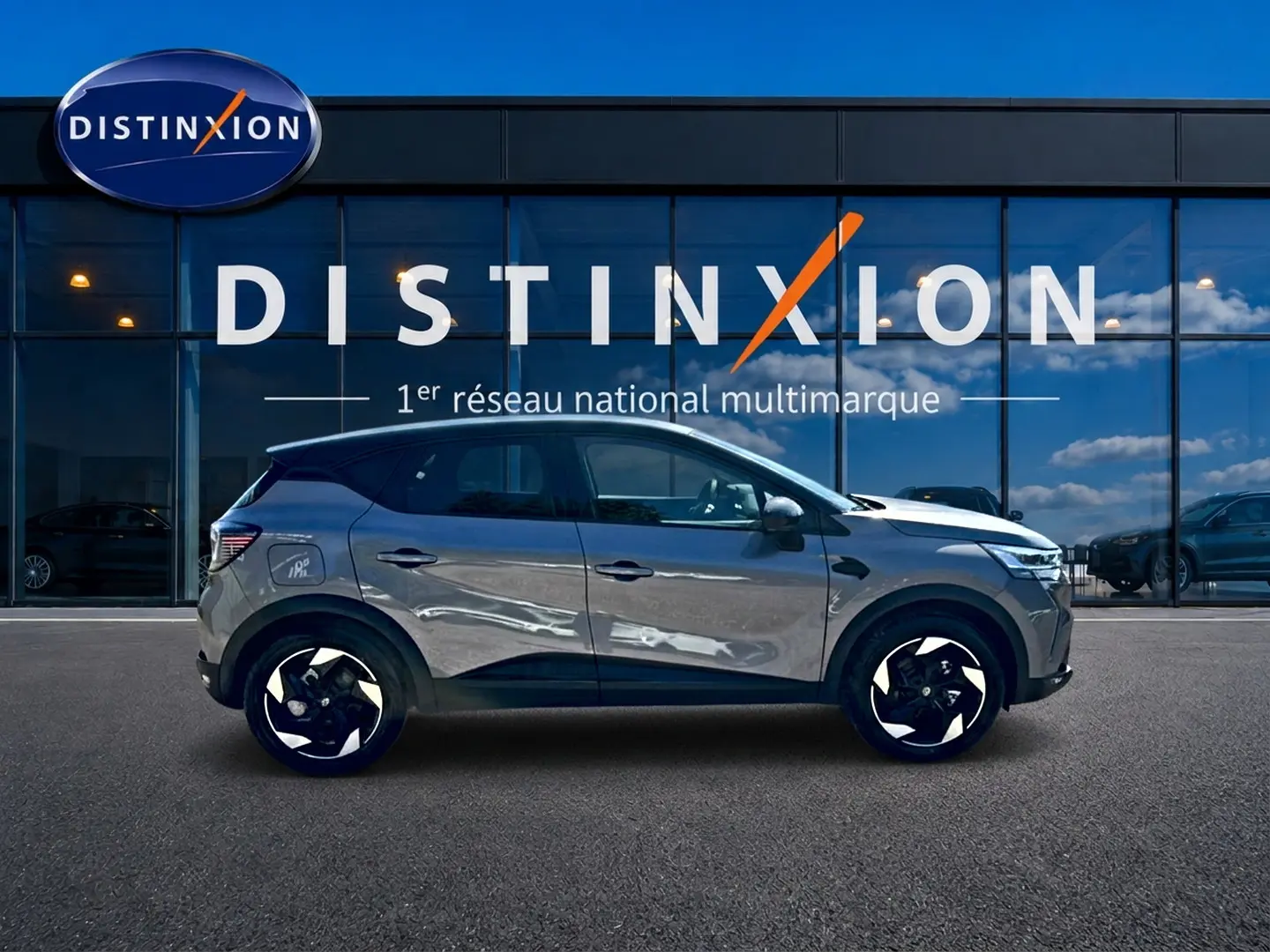 Profil droit du Renault Captur gris cassiopée 2026 stationné devant une vitrine Distinxion.