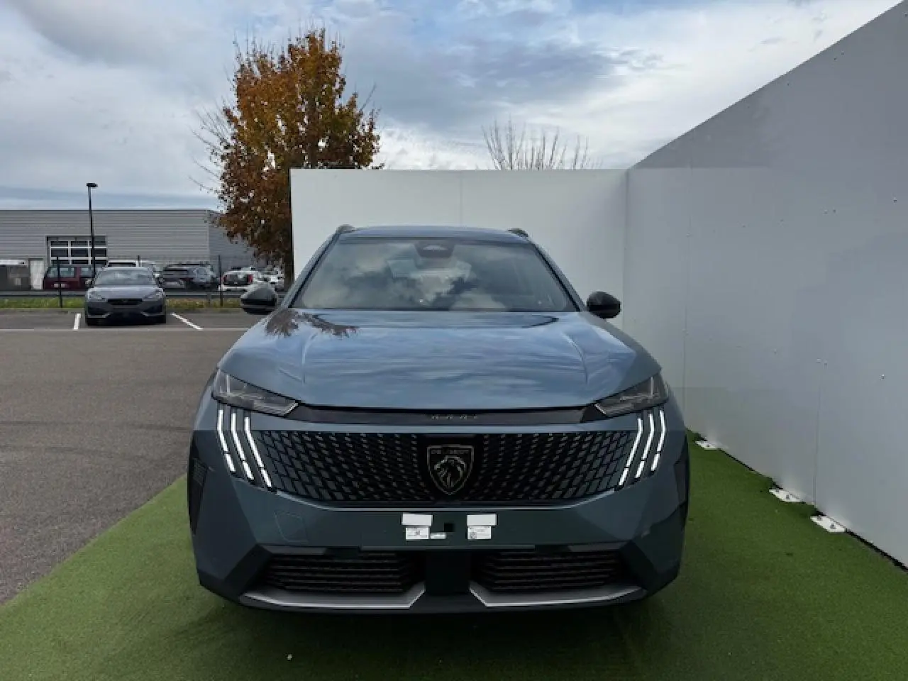 Vue frontale du Peugeot 5008 bleu Ingaro avec calandre noire et feux LED à griffes distinctifs allumés