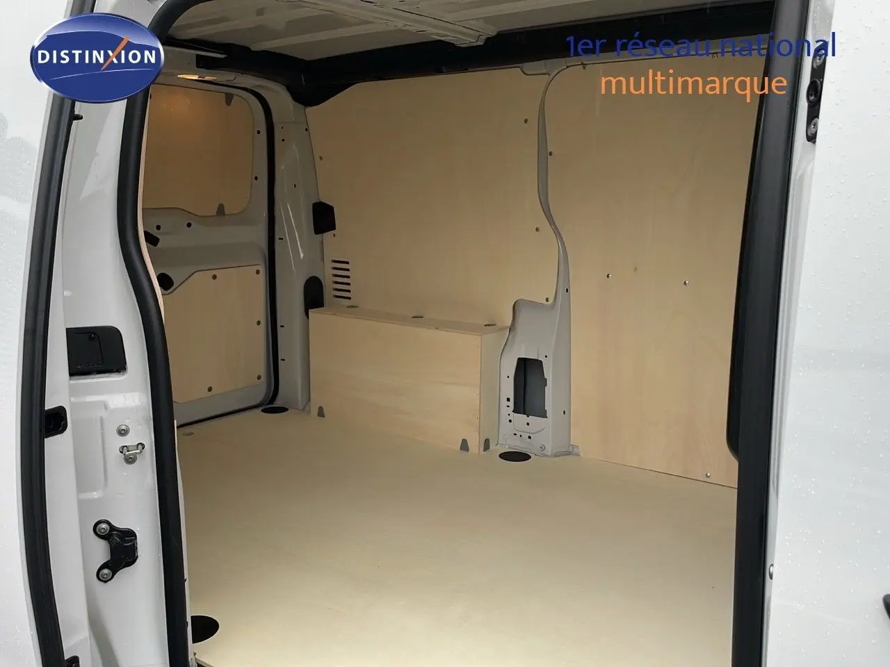 Intérieur du fourgon blanc Peugeot Expert M 1.5 BlueHDi 120ch vu de la porte latérale ouverte, avec aménagement bois clair.