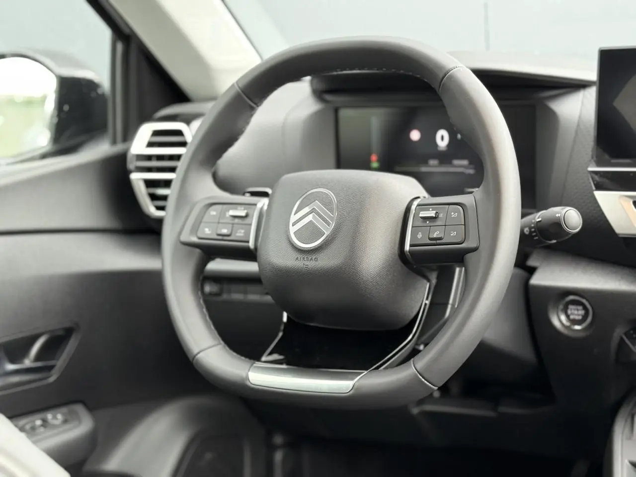 Vue rapprochée du volant cuir noir de la Citroën C4 2025 avec commandes intégrées et tableau de bord numérique.