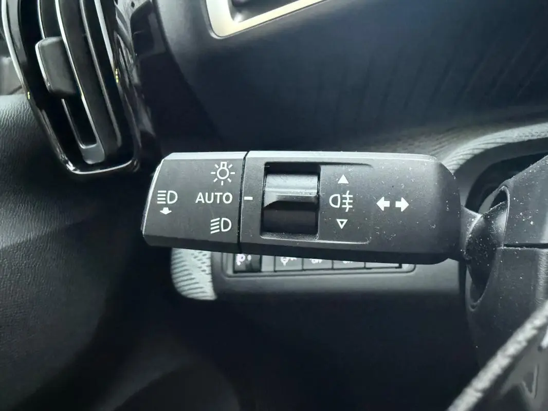 Gros plan sur la commande des feux avec réglage automatique sur le côté gauche du tableau de bord gris du Citroën C3 2025.