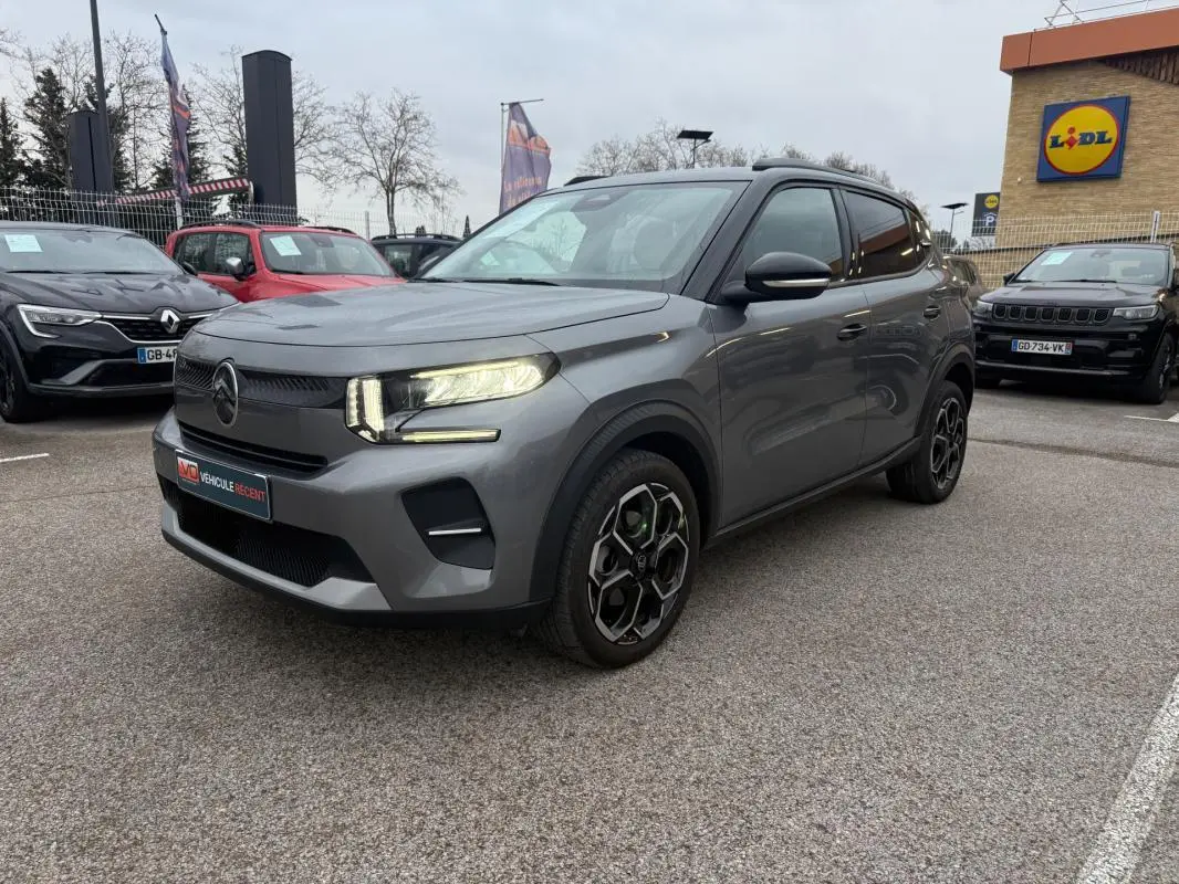 Citroën C3 gris vue 3/4 avant droit, avec jantes alliage 17 pouces et barres de toit visibles en extérieur.