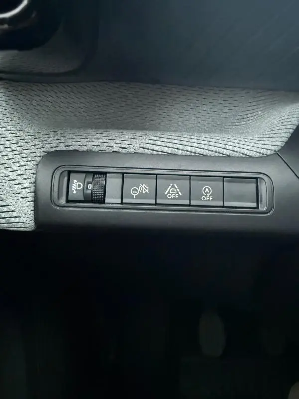 Vue rapprochée des commandes de réglage d’éclairage et d’aide à la conduite sur la planche de bord d’une Citroën C3 gris 2025.