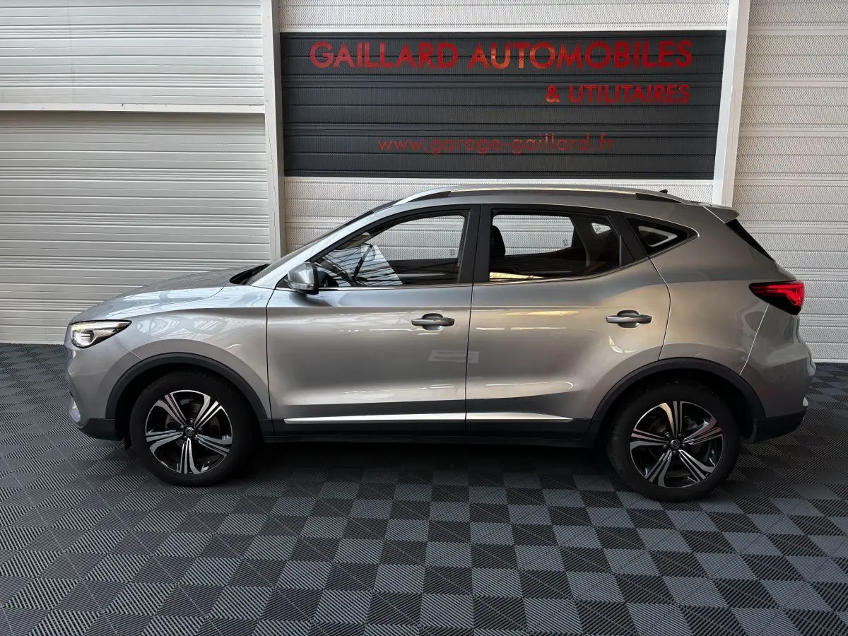 Vue de profil côté gauche d’un MG ZS gris clair 2022, avec jantes alliage et toit ouvrant visible.