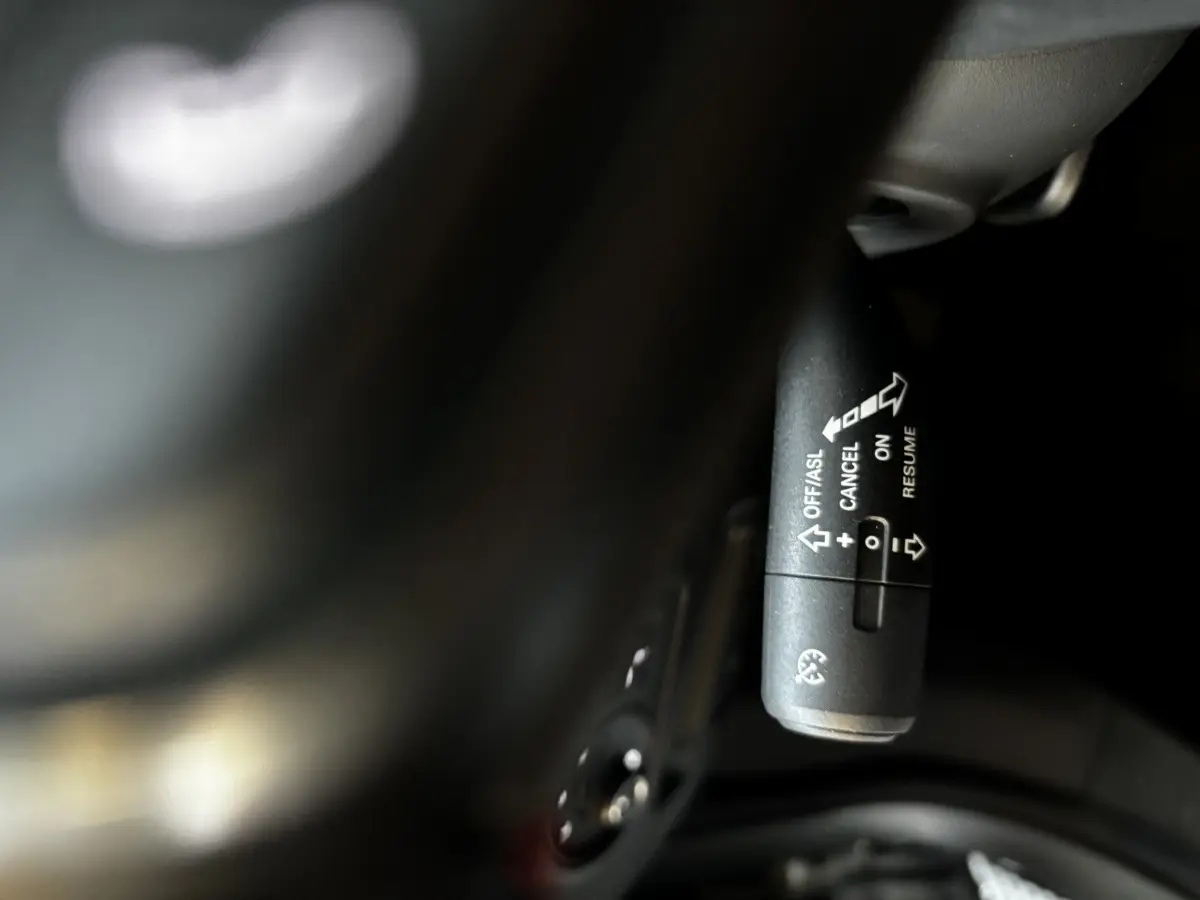 Gros plan sur la commande de régulateur de vitesse noire, à droite du volant d’un MG ZS gris clair 2022.