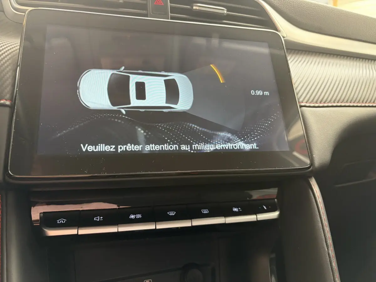 Écran tactile central du MG ZS 2022 affichant l’aide au stationnement avec interface en 3D, intérieur noir et surpiqûres rouges.