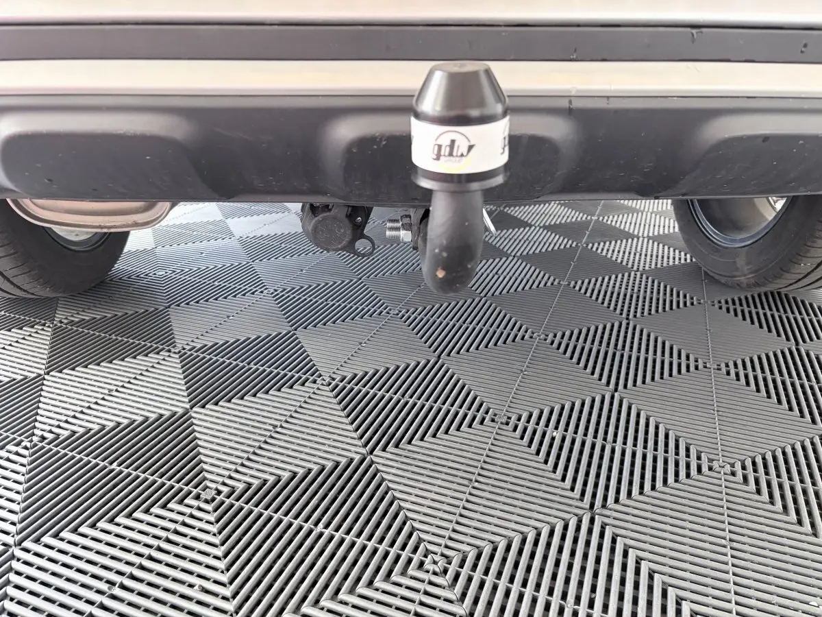 Vue rapprochée de l'attelage d'une MG ZS gris clair, sous le pare-chocs arrière sur sol carrelé.