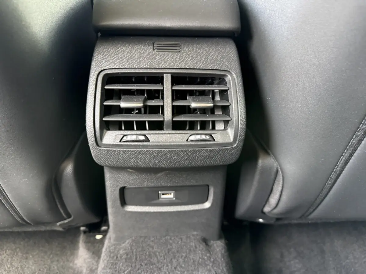 Vue rapprochée des aérateurs arrière noirs et prise USB entre les sièges avant en cuir noir du MG ZS gris clair.