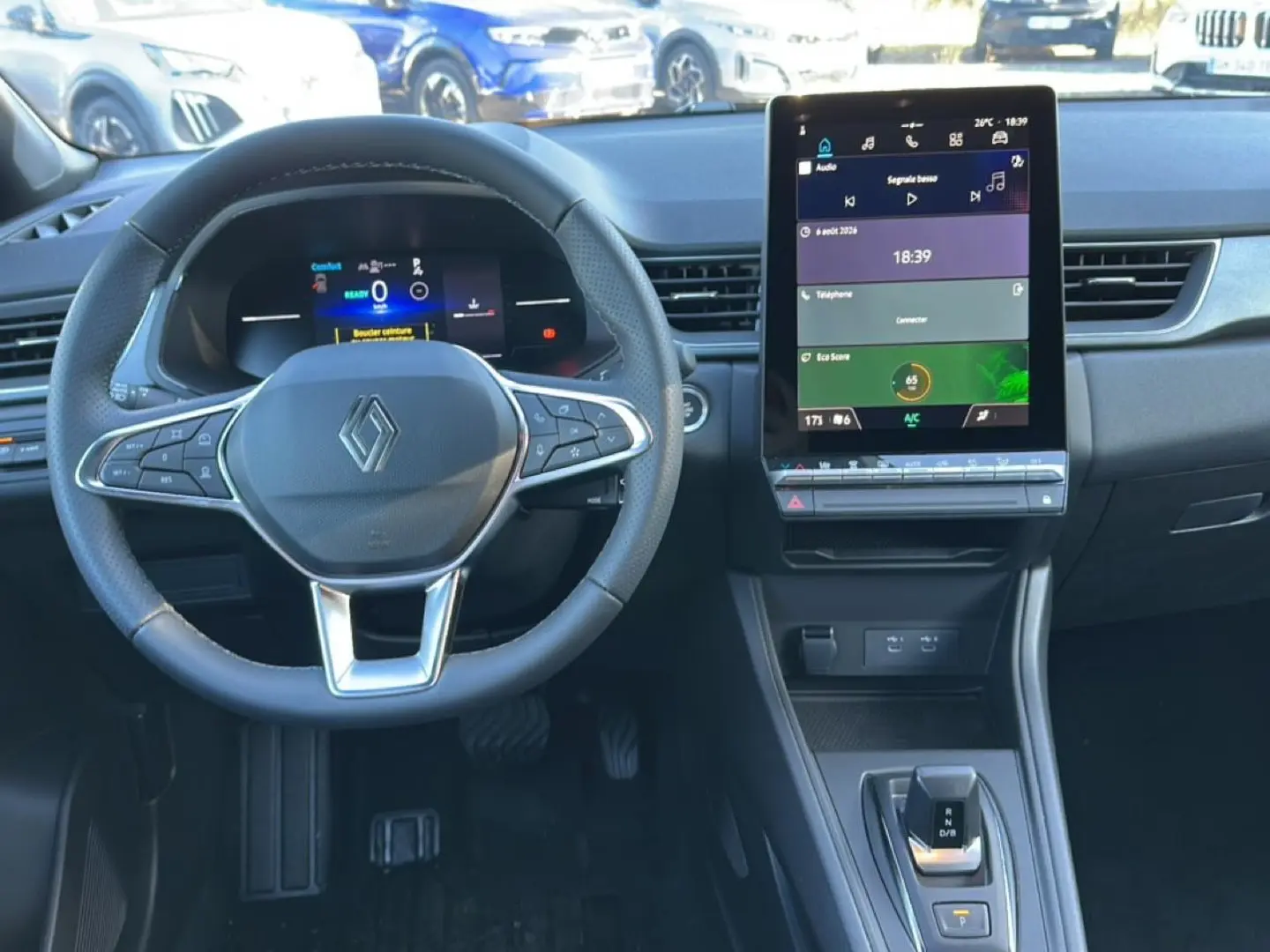 Vue intérieure avant du tableau de bord du Renault Captur 2026 avec volant multifonction et écran tactile vertical.