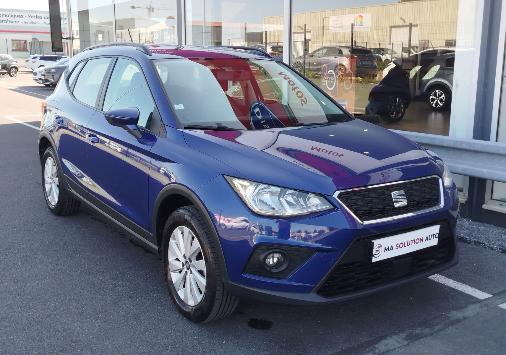 SEAT Arona bleu électrique vu en 3/4 avant droit, avec calandre noire et jantes alliage argentées.