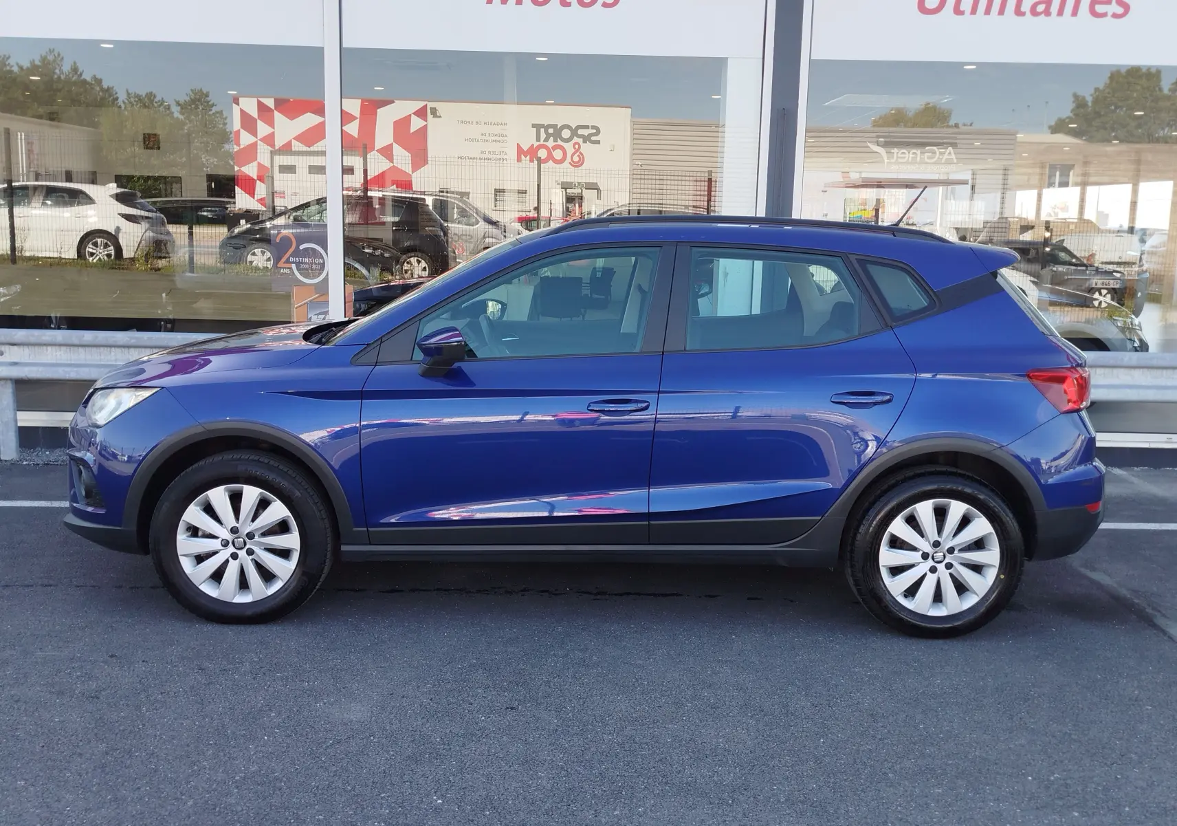 Vue de profil côté gauche d'une SEAT Arona bleu électrique avec jantes alliage et protections noires sur les bas de caisse.