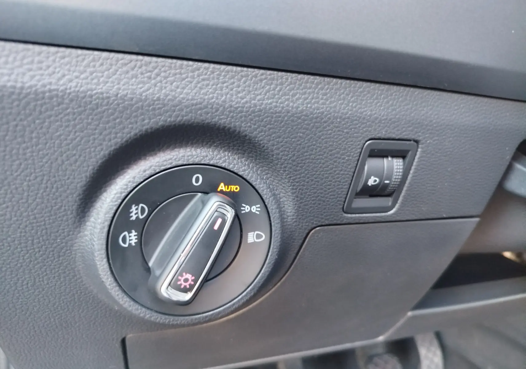 Gros plan sur la molette de réglage des phares du tableau de bord d'une SEAT Arona bleu électrique de 2019.