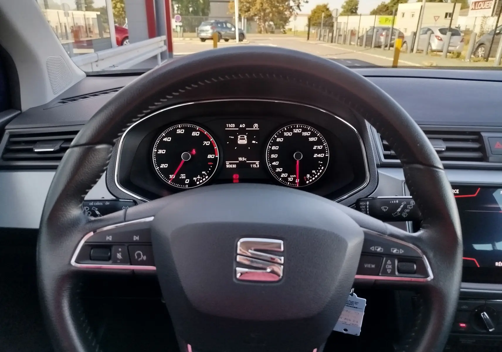Vue intérieure du tableau de bord et volant du SEAT Arona bleu électrique, avec commandes au volant et affichage numérique.