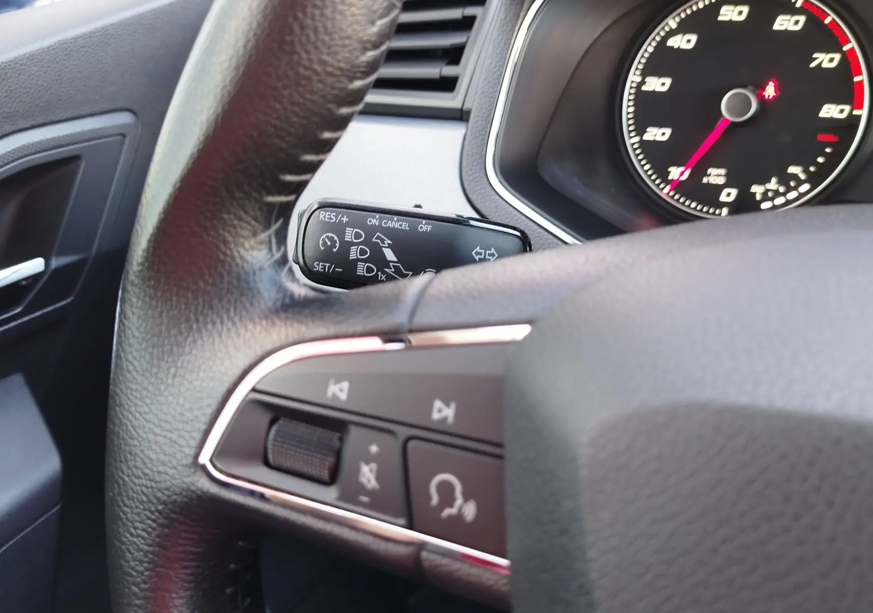 Gros plan sur le volant et le combiné d'instruments du SEAT Arona 2019, montrant les commandes audio et le compteur de vitesse.