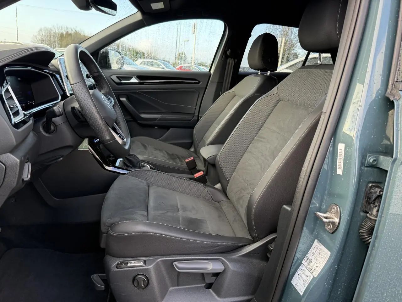 Vue côté conducteur de l'intérieur du Volkswagen T-Roc bleu pétrole, sièges avant en tissu et alcantara gris foncé.
