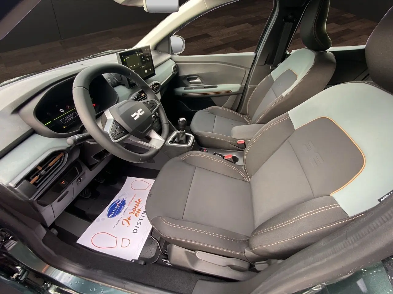 Vue intérieure côté conducteur de la Dacia Sandero Stepway 2026 avec sièges tissu gris noir et tableau de bord moderne.