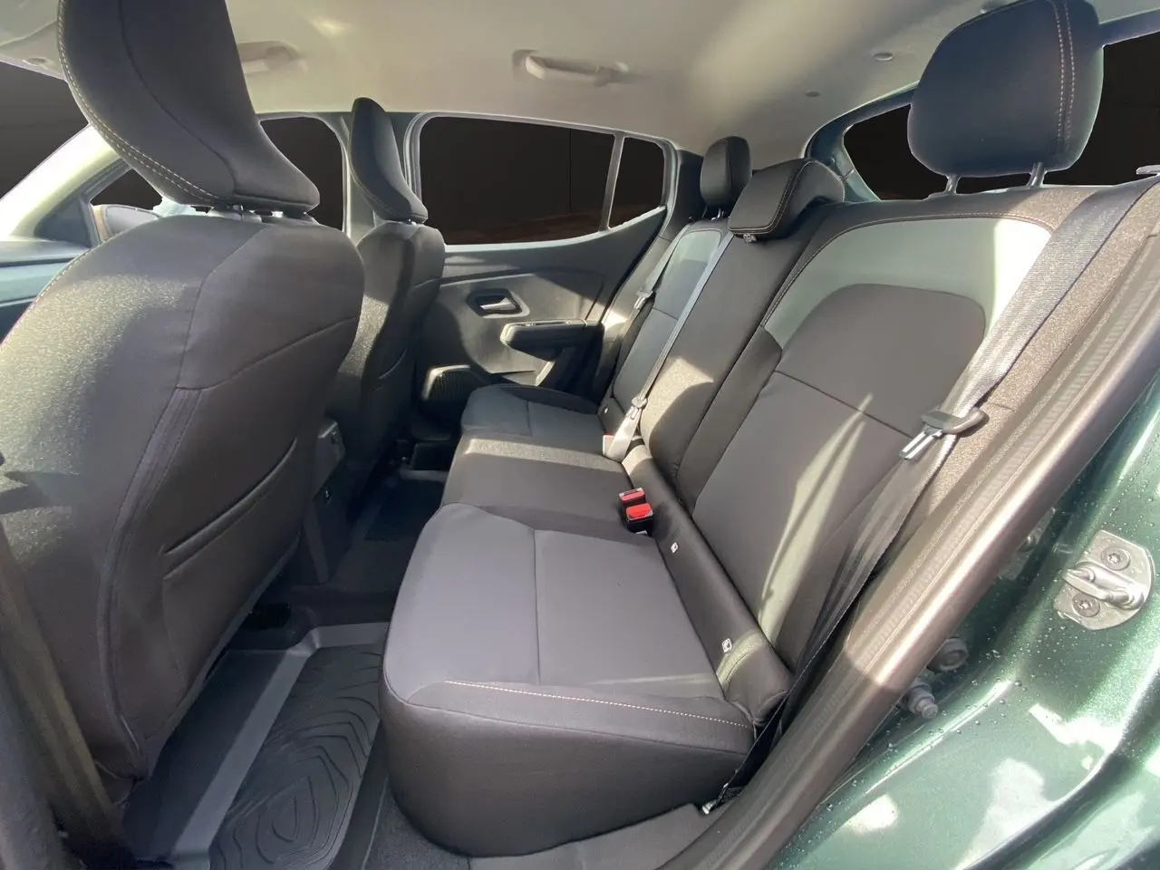 Vue côté droit des sièges arrière en tissu gris noir du Dacia Sandero Stepway Vert Cèdre avec porte ouverte.