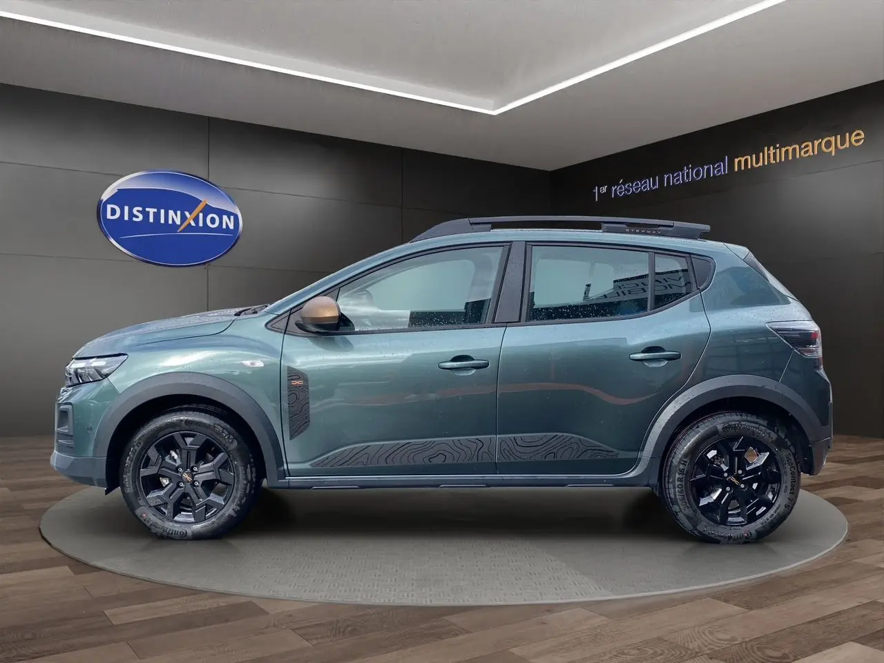 Vue de profil côté gauche d'une Dacia Sandero Stepway TCE 110 Extreme vert cèdre avec jantes alliage noires et détails décoratifs noirs.