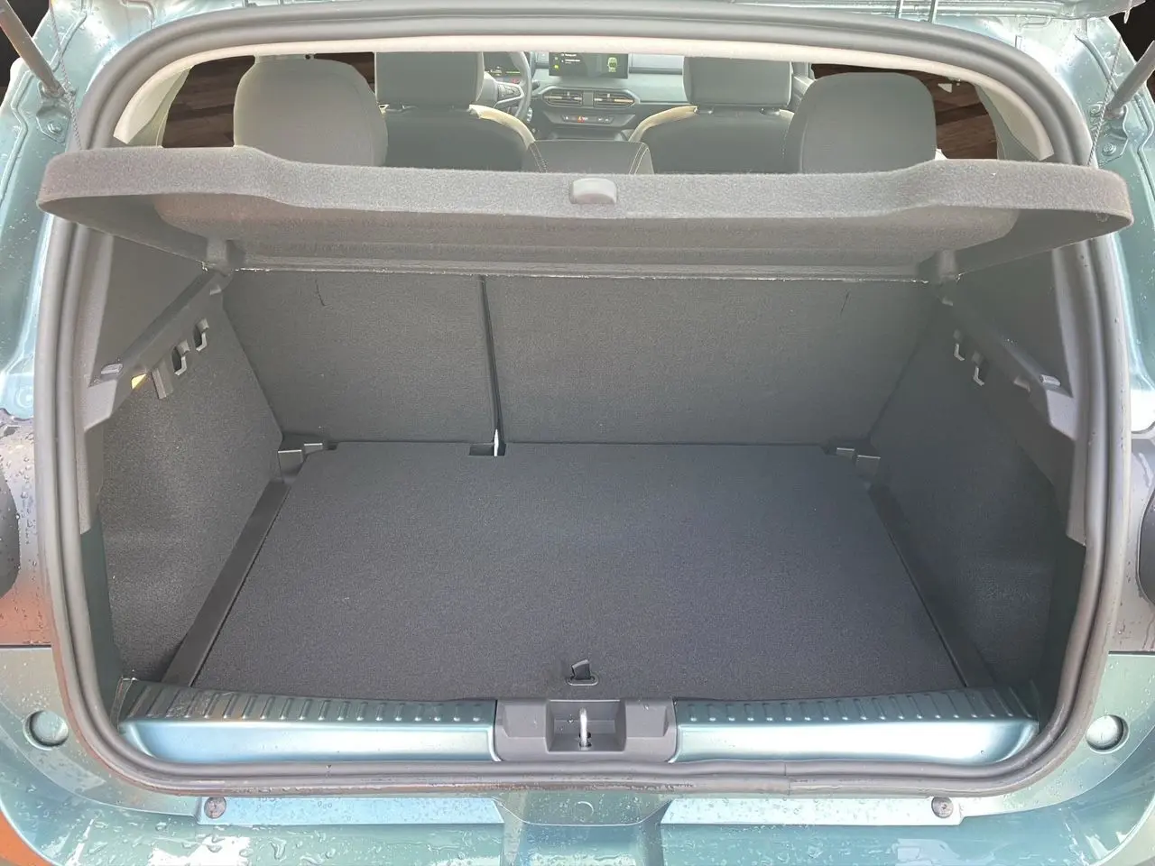 Coffre ouvert vu de l’arrière d’une Dacia Sandero Stepway 2026 vert cèdre, montrant l’espace de chargement et l’intérieur gris noir.