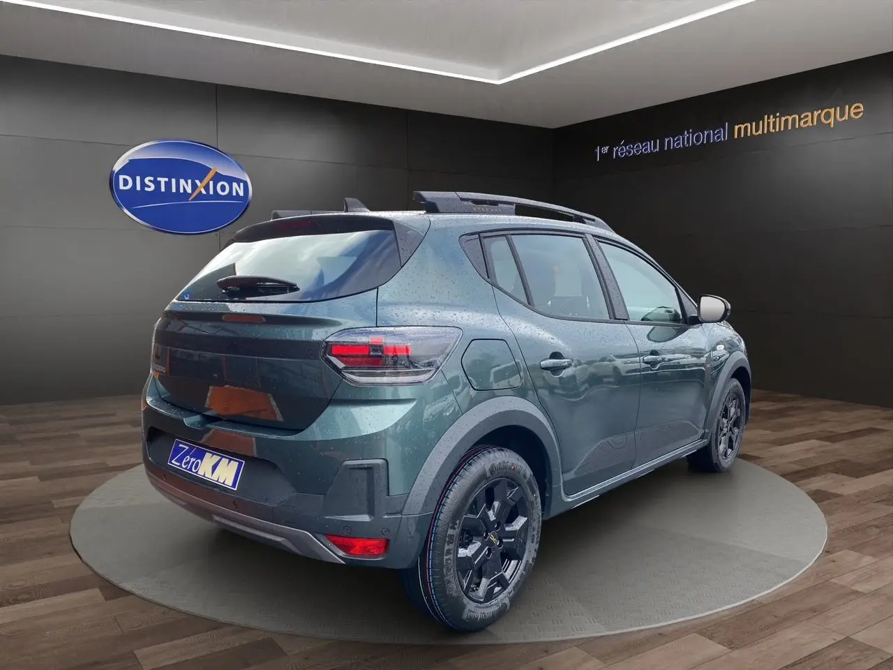 Vue 3/4 arrière droite d'une Dacia Sandero Stepway TCE 110 Vert Cèdre avec jantes alliage noires et toit noir.