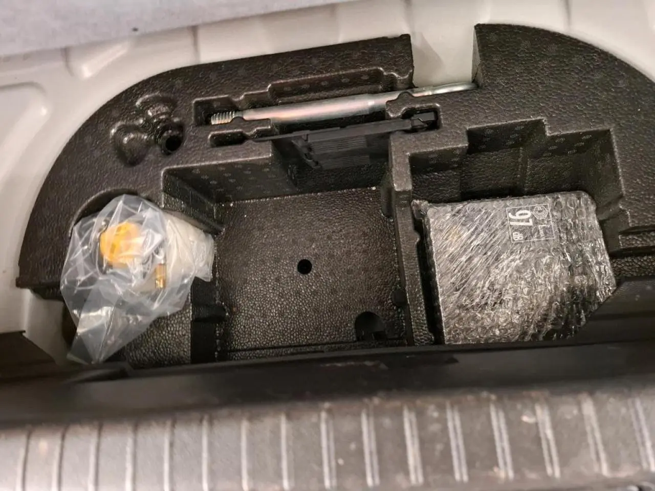 Coffre à outils et accessoires sous plancher de coffre de Peugeot 208 e-136 blanc, vue de dessus.