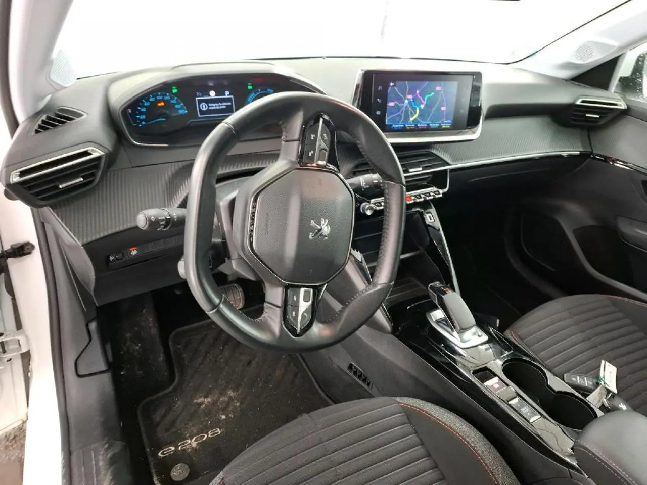 Vue intérieure côté conducteur du Peugeot 208 e-136 blanc, avec volant compact et écran tactile central.