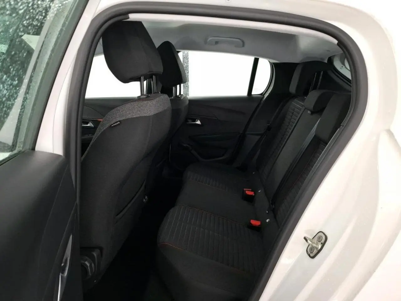 Vue intérieure côté gauche sur la banquette arrière noire avec surpiqûres orange d'une Peugeot 208 blanche électrique 2020.