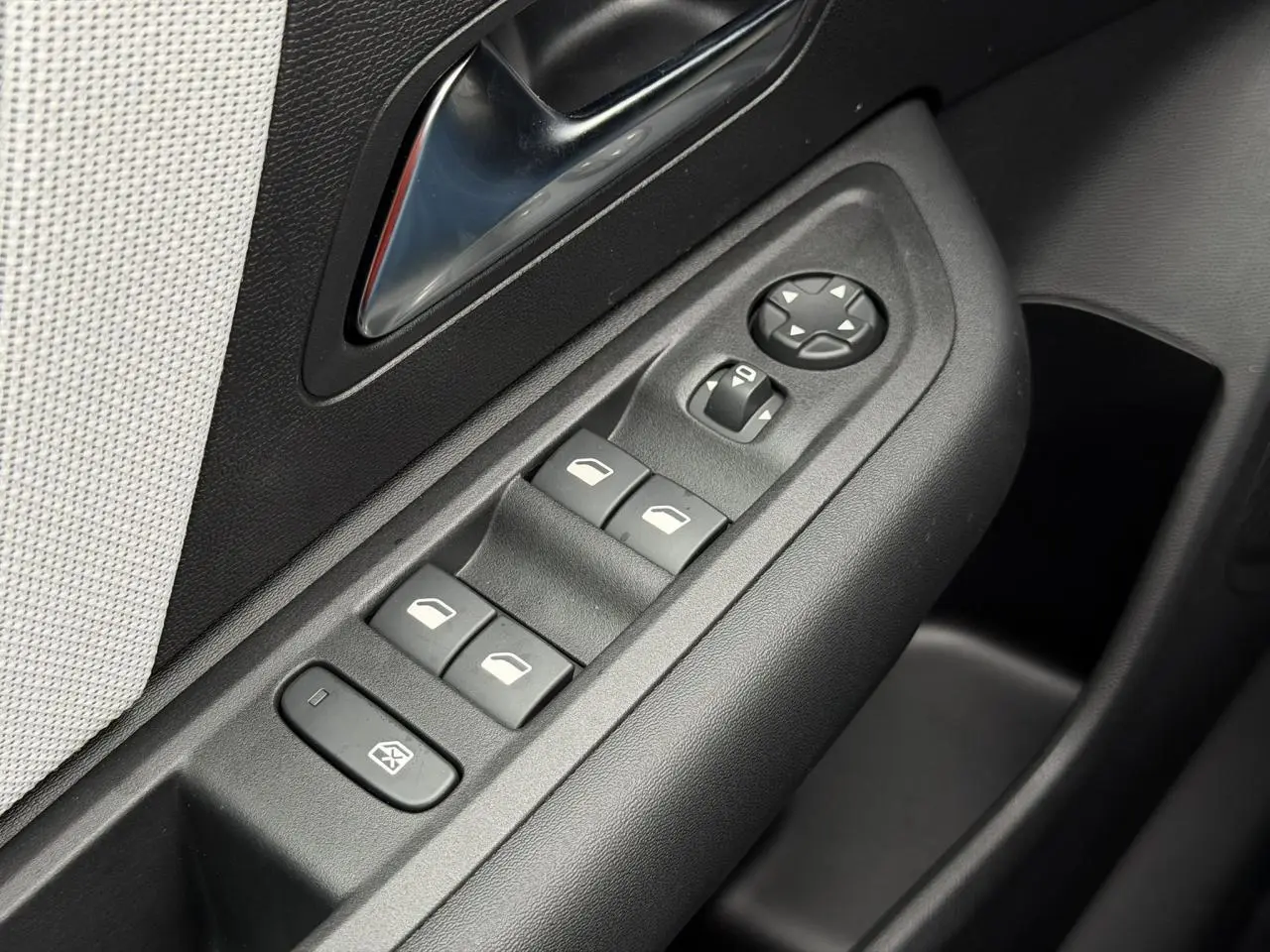 Gros plan sur les commandes de lève-vitres et rétroviseurs côté conducteur de la Citroën C4 gris Mercury, intérieur noir et tissu clair.