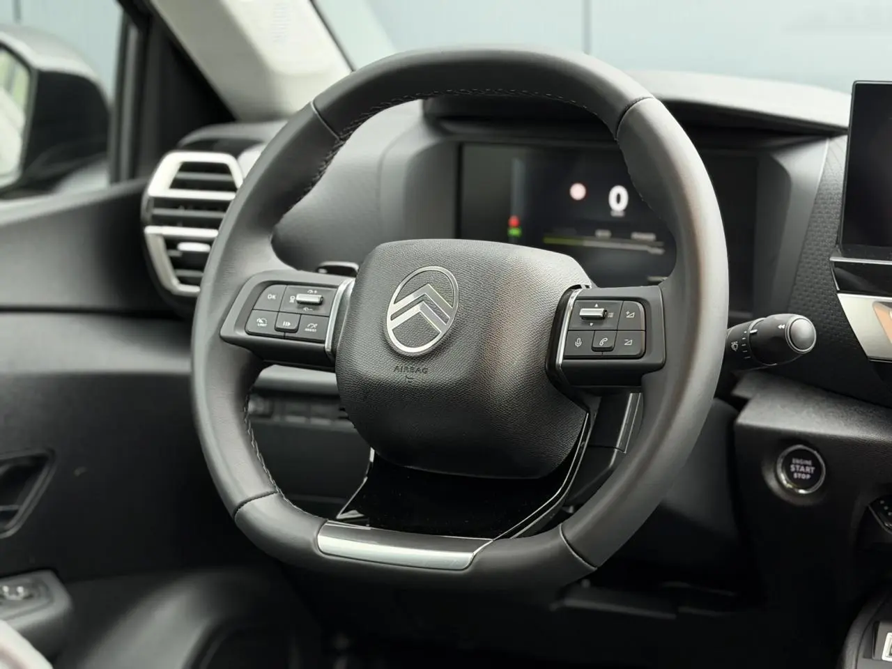 Vue rapprochée du volant cuir noir de la Citroën C4 2025 avec commandes intégrées et tableau de bord numérique.
