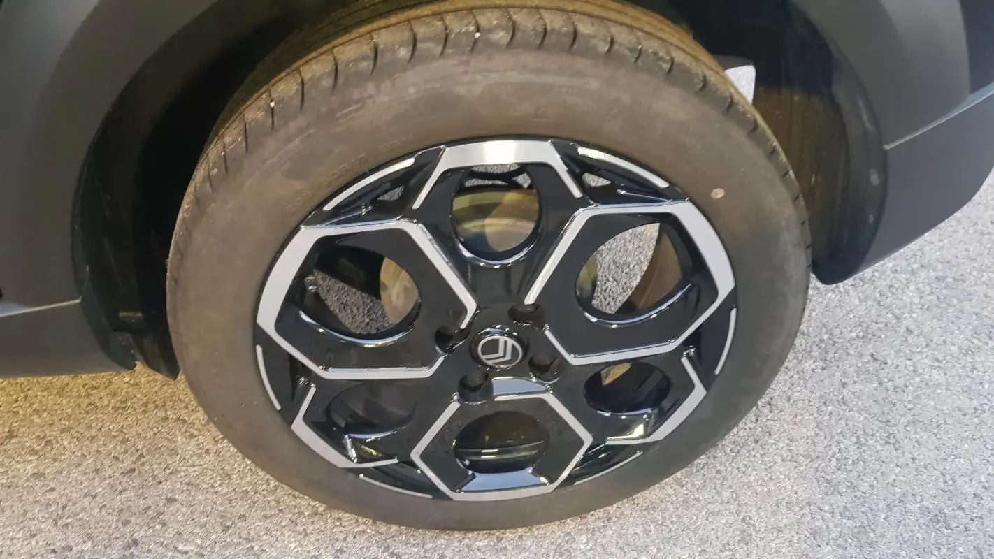Gros plan sur la jante alliage 17 pouces noire et argentée du côté avant gauche d'une Citroën C3 noire.