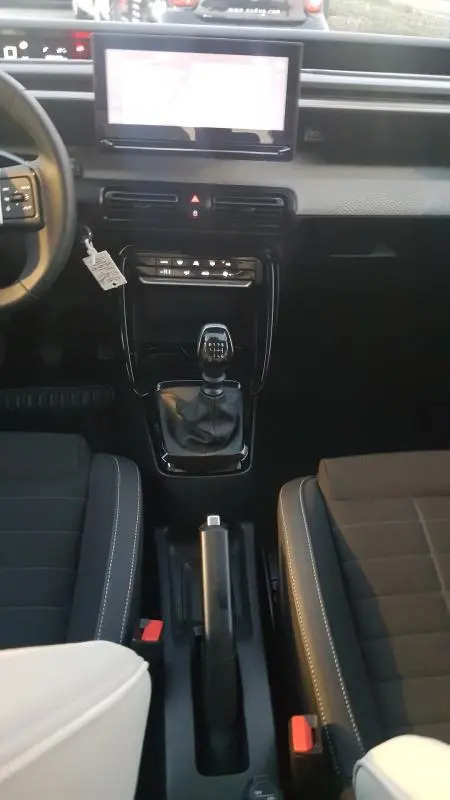 Vue intérieure centrée sur la console centrale et levier de vitesses manuelle d'une Citroën C3 noire 2025.