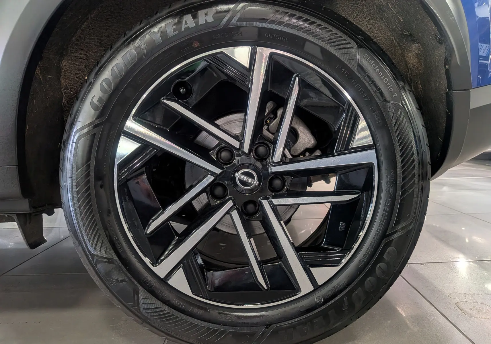 Gros plan sur la roue avant droite du Nissan Juke Hybrid 2025 bleu magnétique, jante alliage noir et argentée.