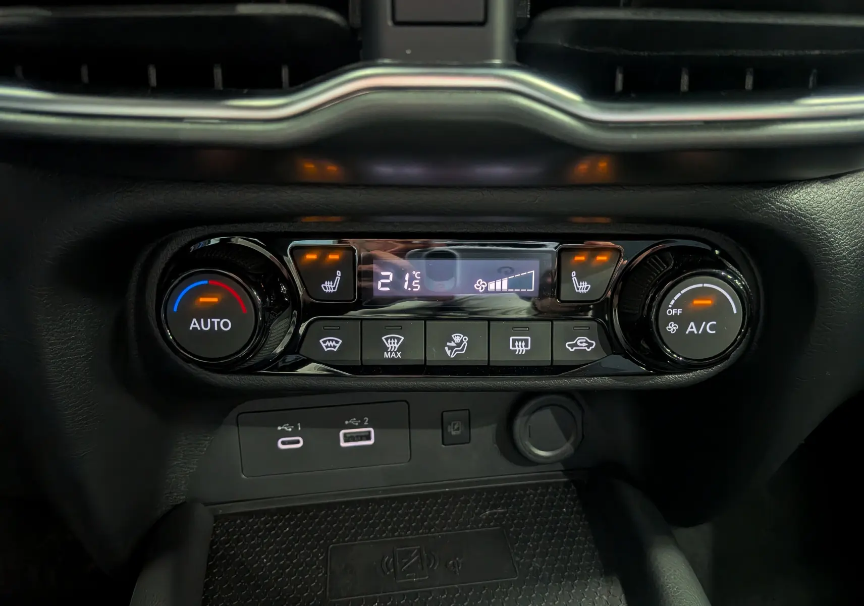 Gros plan sur la console centrale du Nissan Juke Hybrid 2025, montrant les commandes de climatisation et les ports USB.