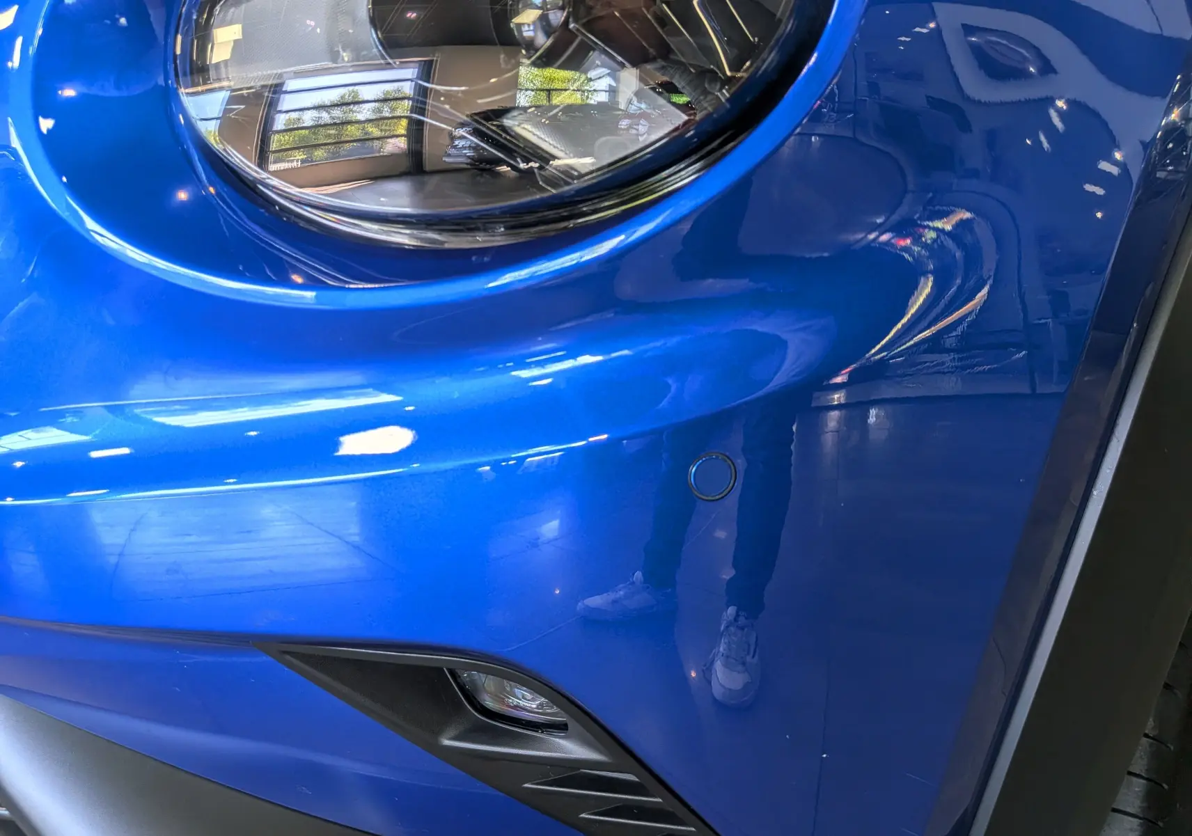 Gros plan sur le phare avant gauche du Nissan Juke 2025 bleu magnétique avec détails du pare-chocs et antibrouillard.