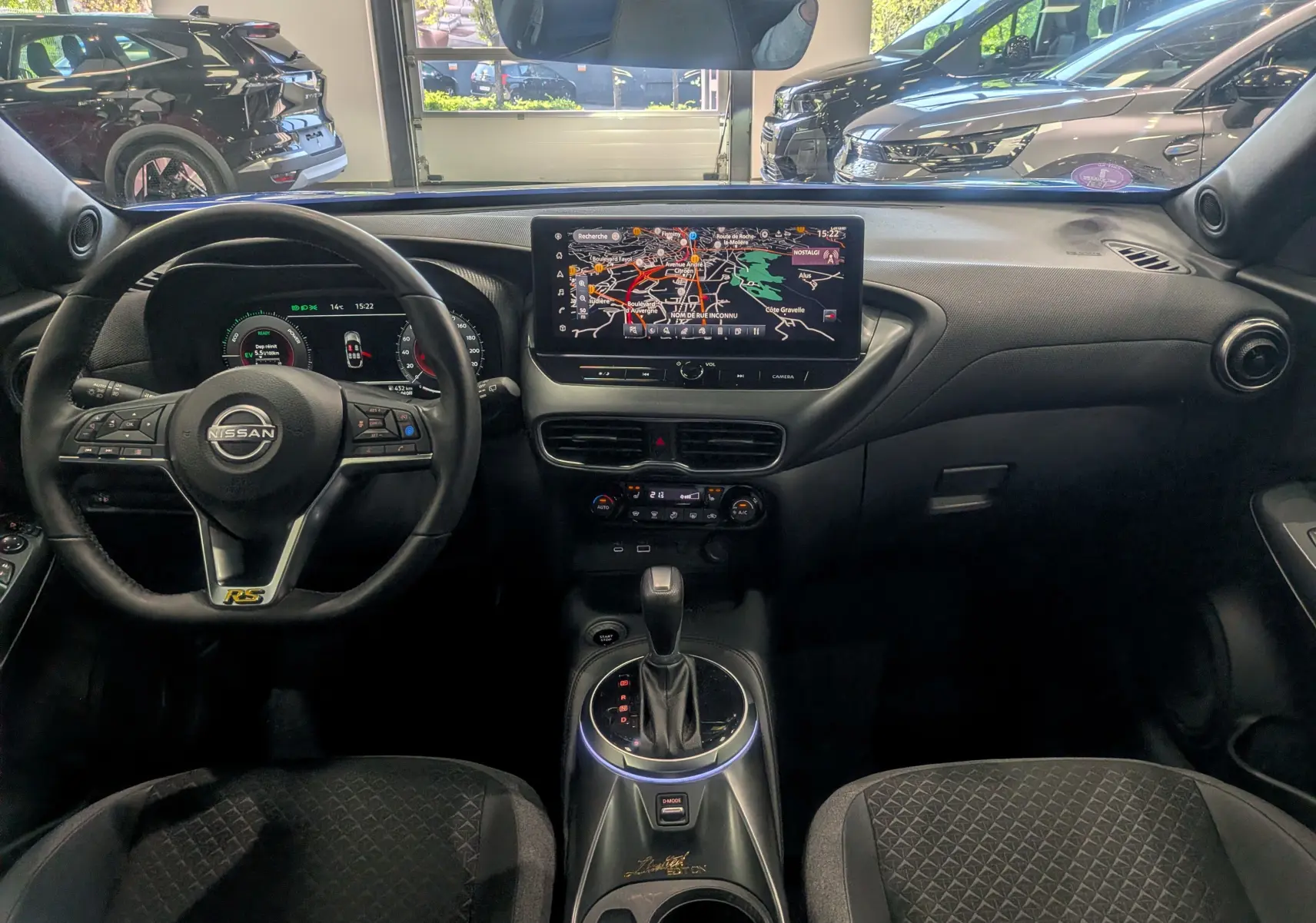 Vue intérieure frontale du Nissan Juke Hybrid 2025, tableau de bord avec écran tactile et volant multifonction noir.