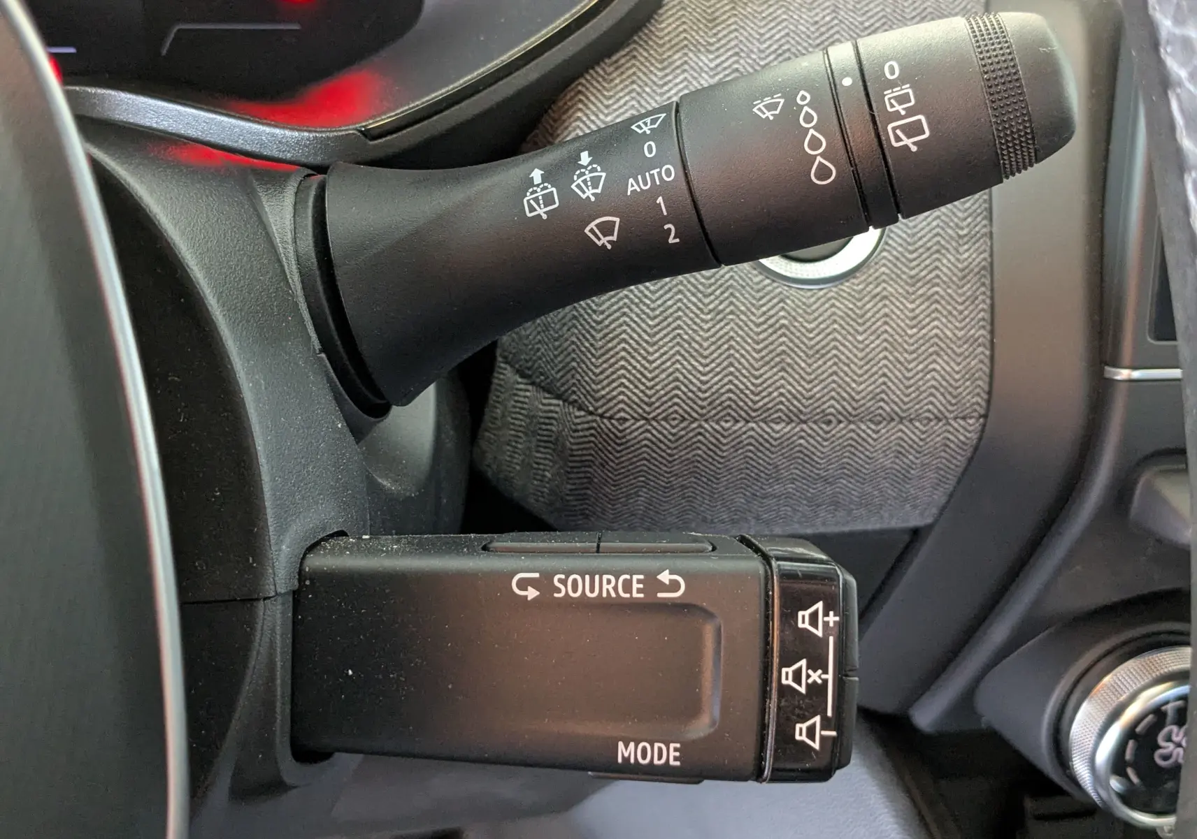 Gros plan sur les commandes au volant côté gauche de la Renault Clio 2025 gris schiste, avec commandes essuie-glace et multimédia.