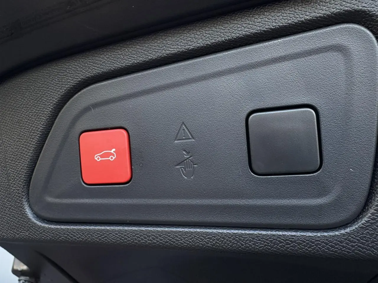 Boutons de commande du hayon électrique, dont un rouge avec icône de coffre, sur panneau intérieur noir du Citroën C5 Aircross Bleu Eclipse.