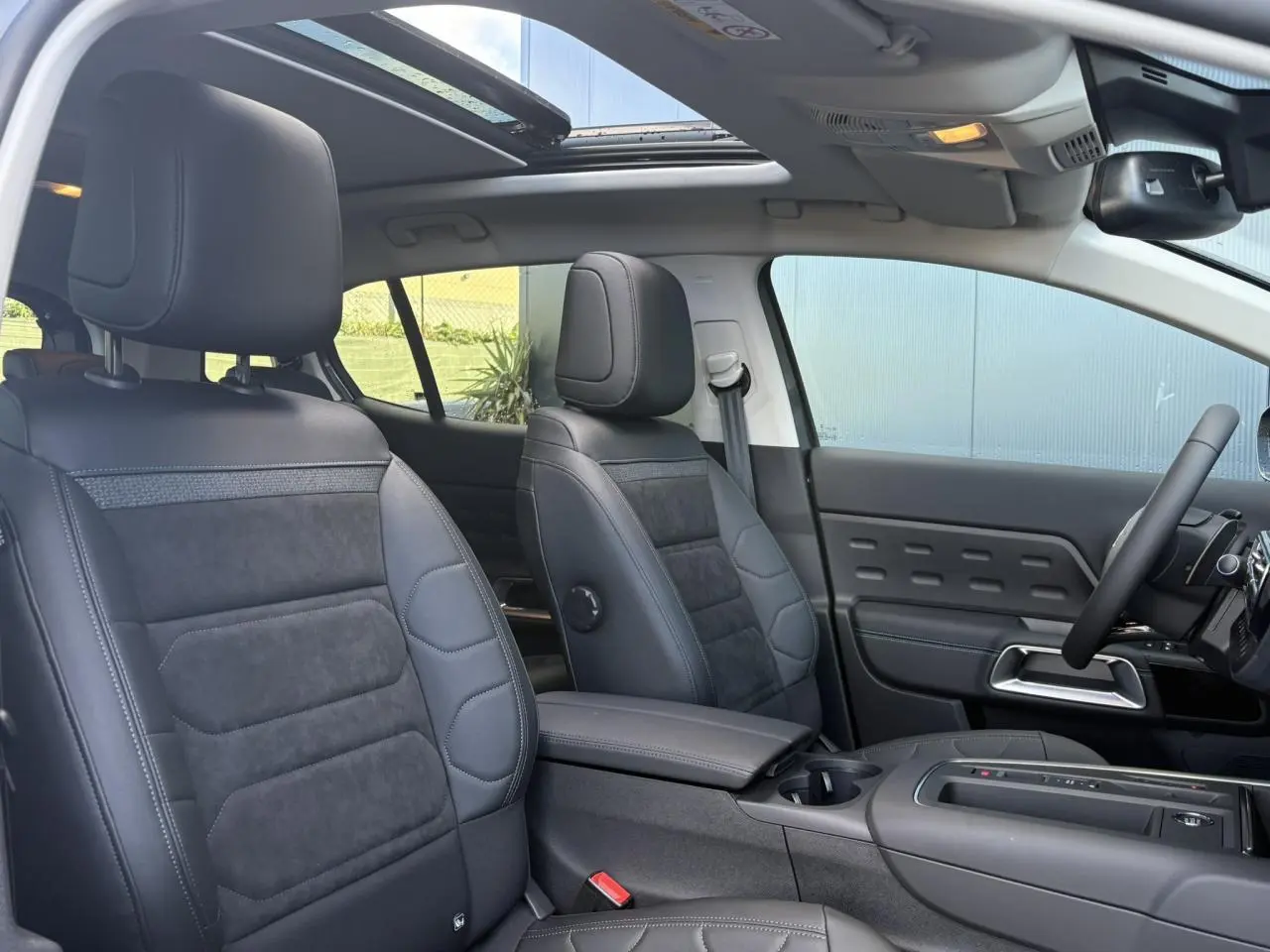 Intérieur avant du Citroën C5 Aircross 2025, sièges Urban Black en Alcantara noir, toit ouvrant panoramique ouvert.