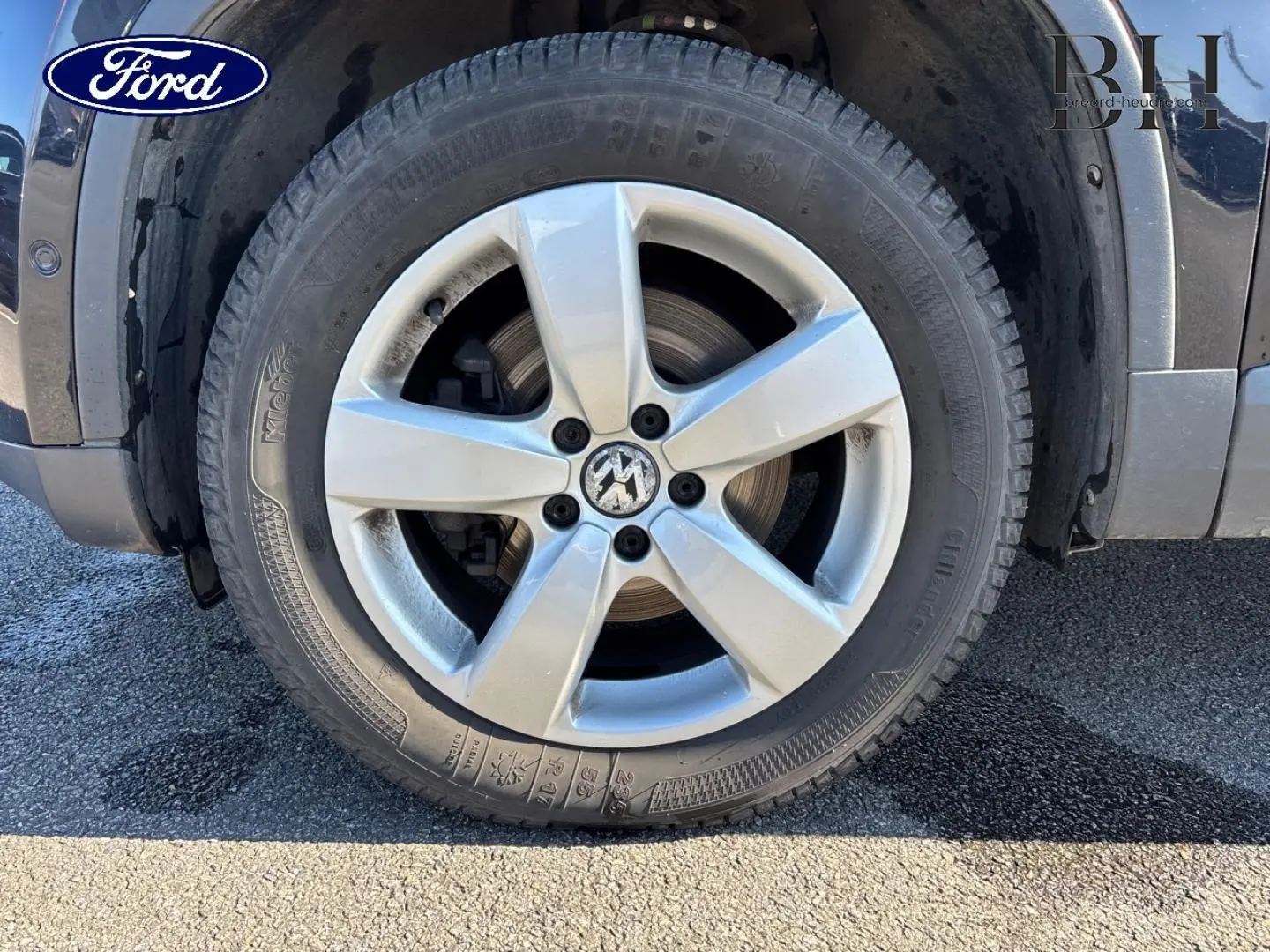 Gros plan sur la roue avant droite d'un Volkswagen Tiguan beige, mettant en valeur la jante alu à cinq branches.