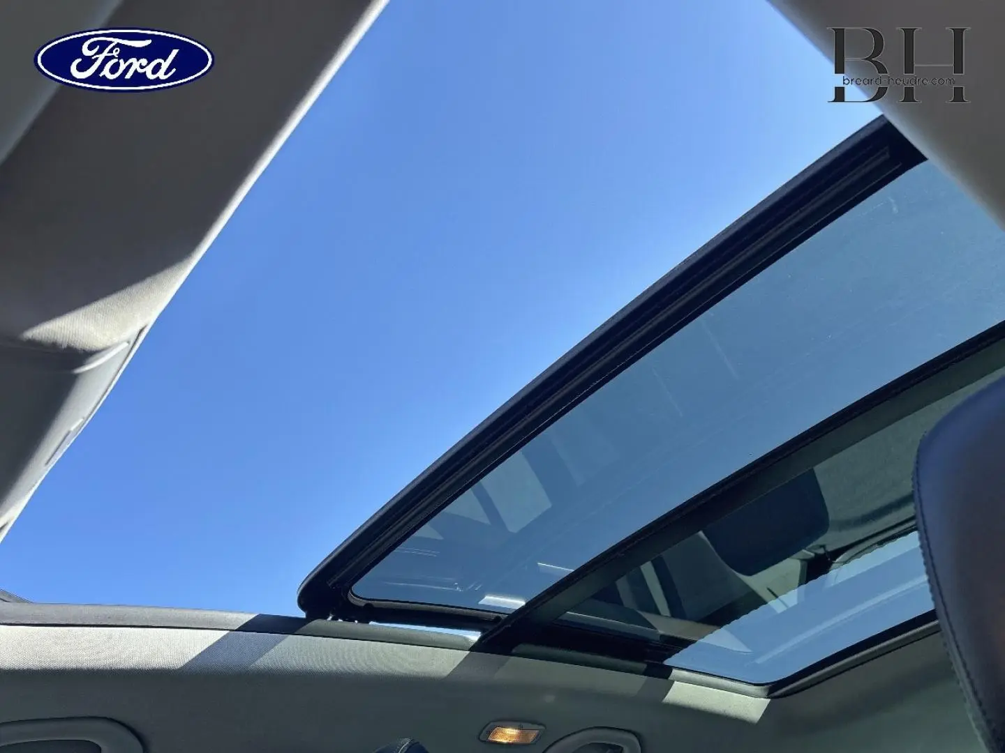 Toit ouvrant panoramique ouvert sur ciel bleu, vue intérieure du Volkswagen Tiguan beige 2010