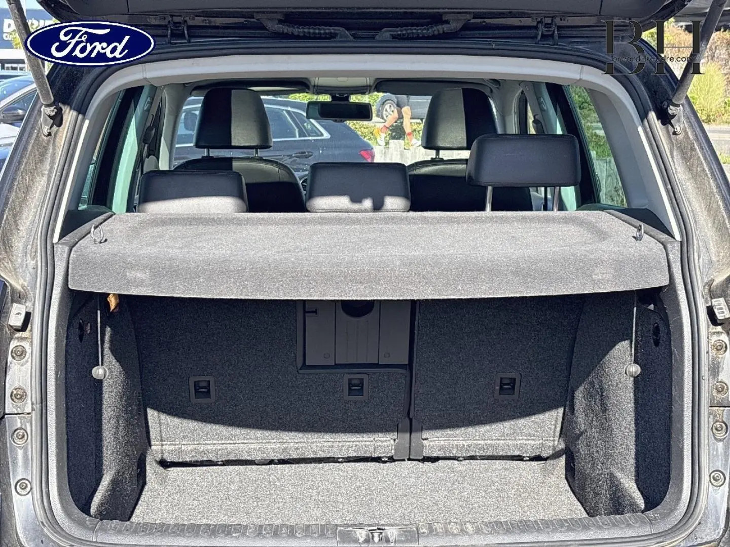 Coffre ouvert d’un Volkswagen Tiguan beige 2010, vue arrière montrant la banquette arrière et la plage arrière.