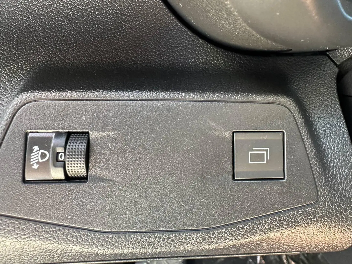 Détail intérieur montrant les commandes de réglage des phares et de l'affichage sur un Citroën Berlingo Kiama Blue.