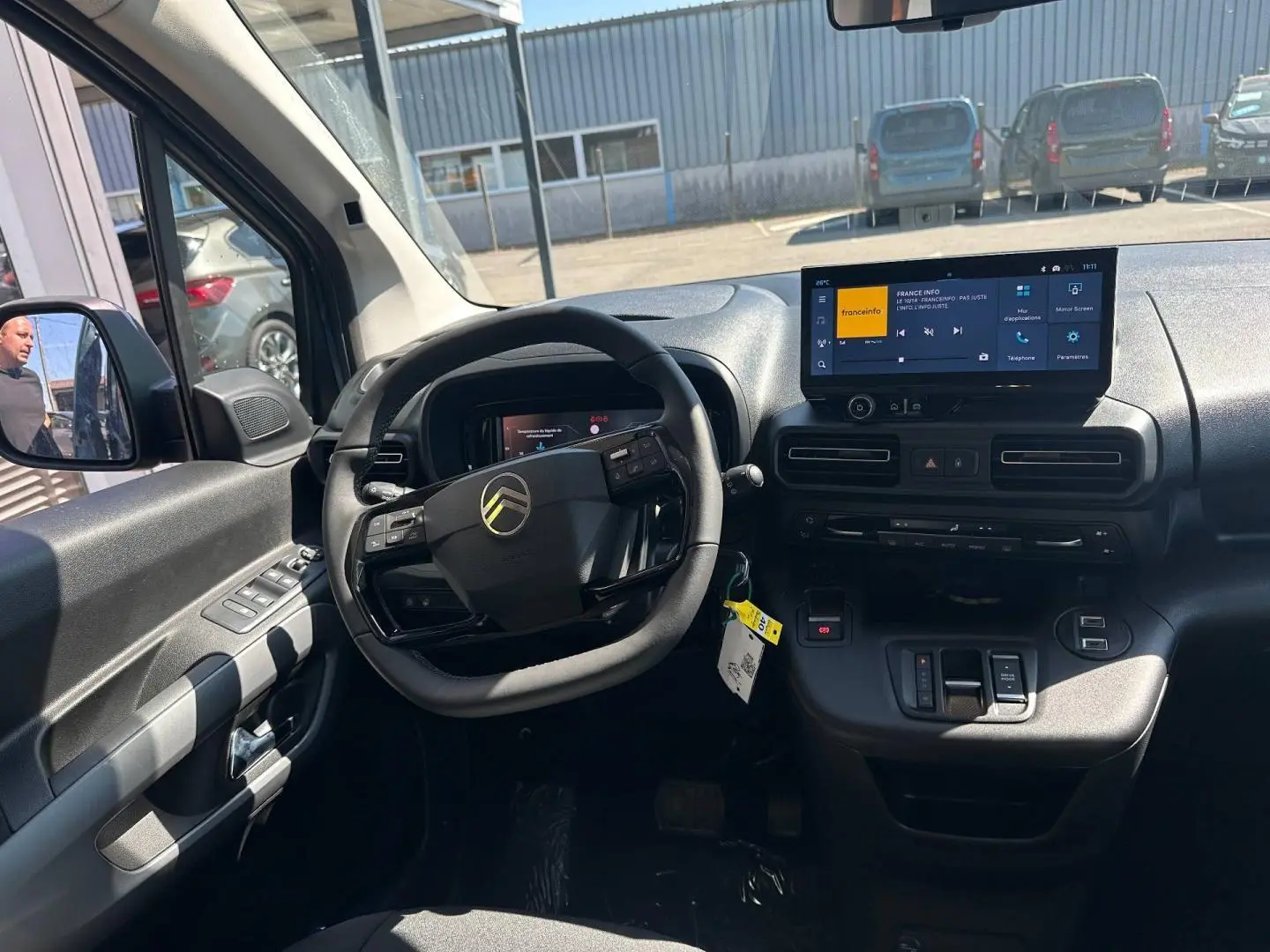 Intérieur du Citroën Berlingo 2026 vu côté conducteur, tableau de bord noir avec écran tactile et volant multifonction.