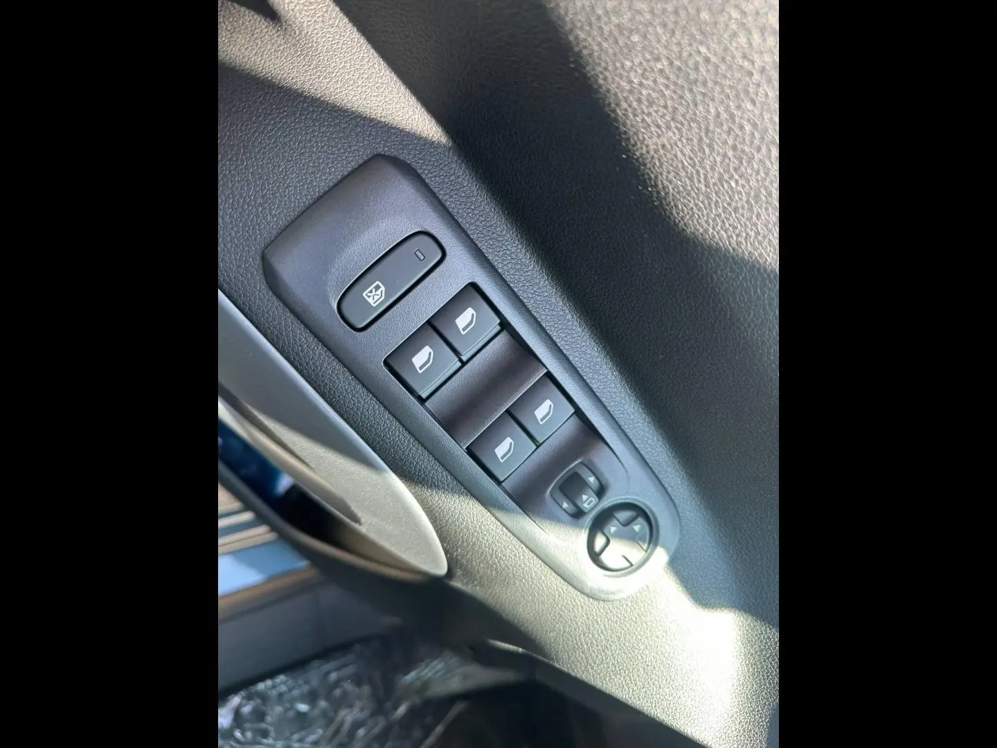 Gros plan sur les commandes des vitres électriques et rétroviseurs du côté conducteur d’un Citroën Berlingo Kiama Blue.