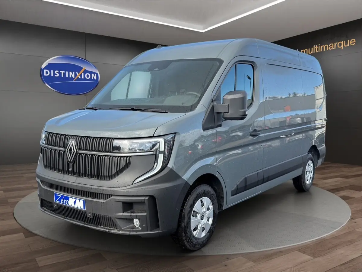 Vue 3/4 avant d’un Renault Master gris métallisé avec calandre noire et feux LED, sur fond intérieur showroom.