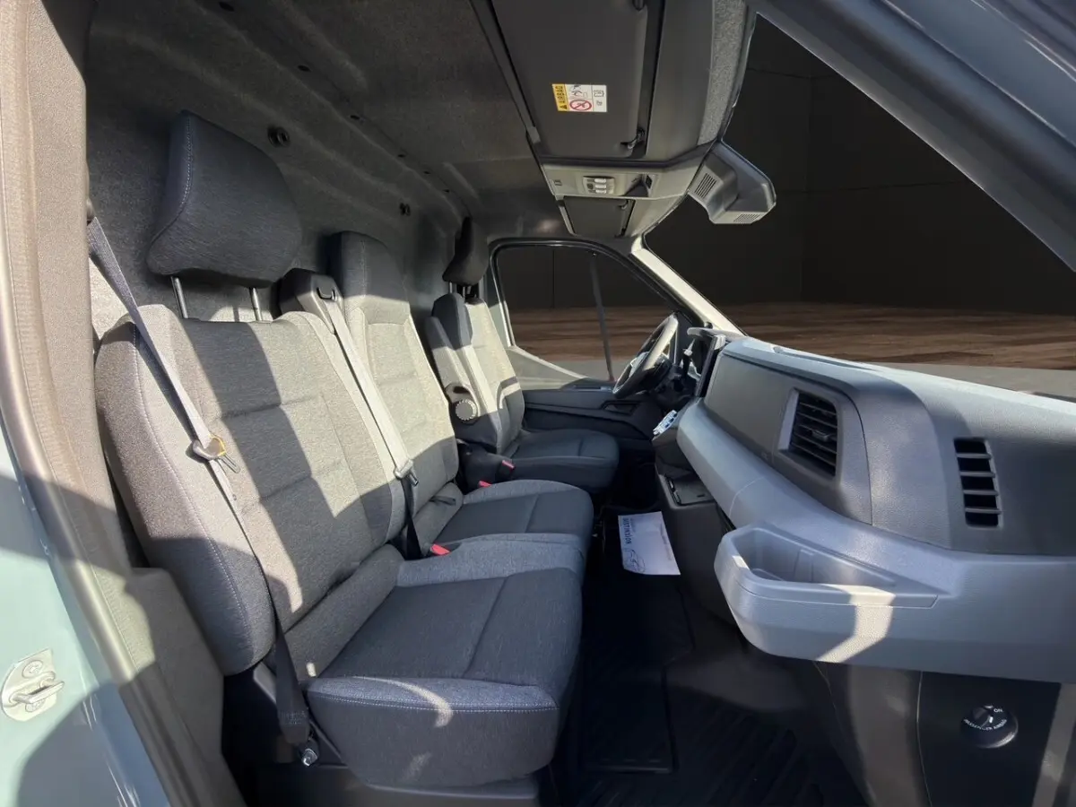 Vue intérieure côté conducteur du Renault Master 2026 avec sièges gris et tableau de bord sobre en plastique gris.