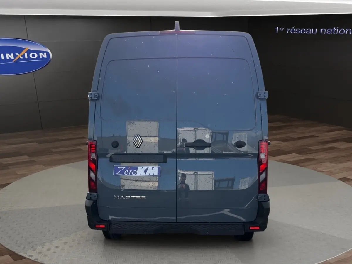 Vue arrière d’un Renault Master gris foncé avec portes battantes et feux arrière verticaux allumés.