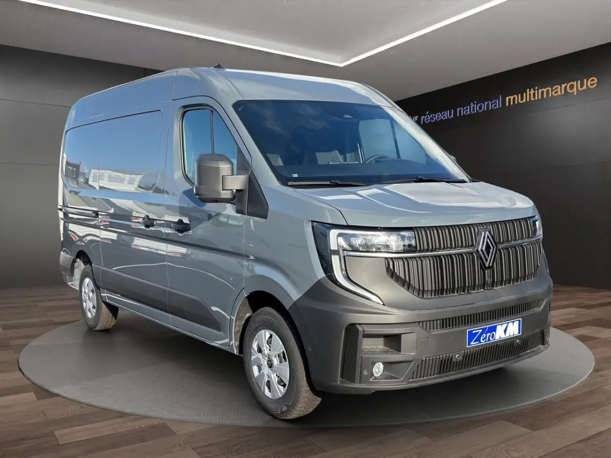 Vue 3/4 avant droite du Renault Master gris avec calandre noire et feux LED, sur plateforme en showroom.